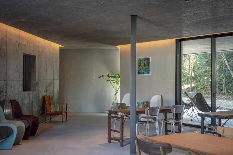Living space with polished concrete floor, cove lighting, and glazed wall opening to the forest