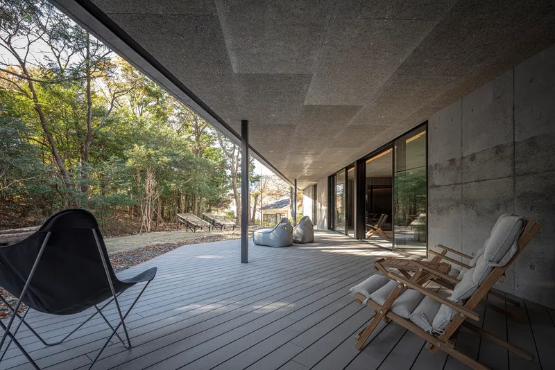 Covered timber deck terrace with folding canvas chairs overlooking wooded hillside in afternoon light