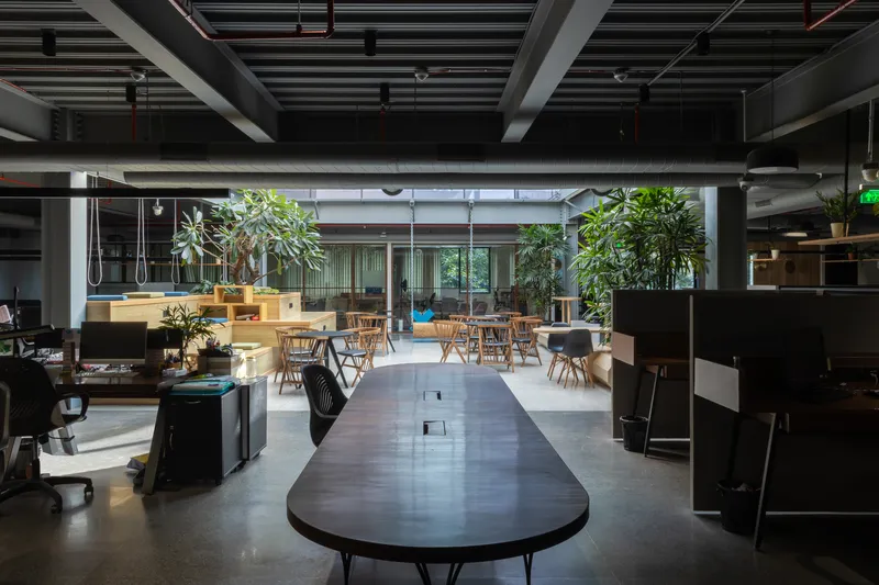 Open-plan office interior with exposed ceiling beams and seating area overlooking glazed courtyard