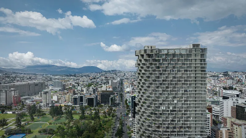 Aerial view of the staggered balcony tower against distant mountains and urban fabric below