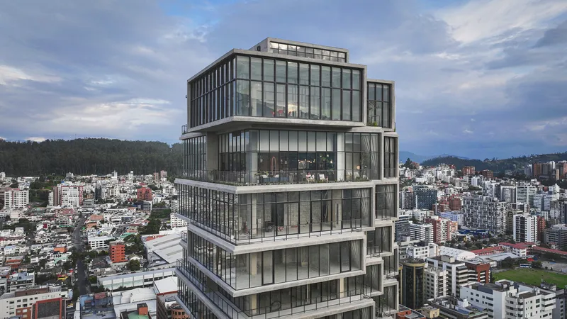 Stepped glass tower with cantilevered floor plates overlooking a dense urban hillside