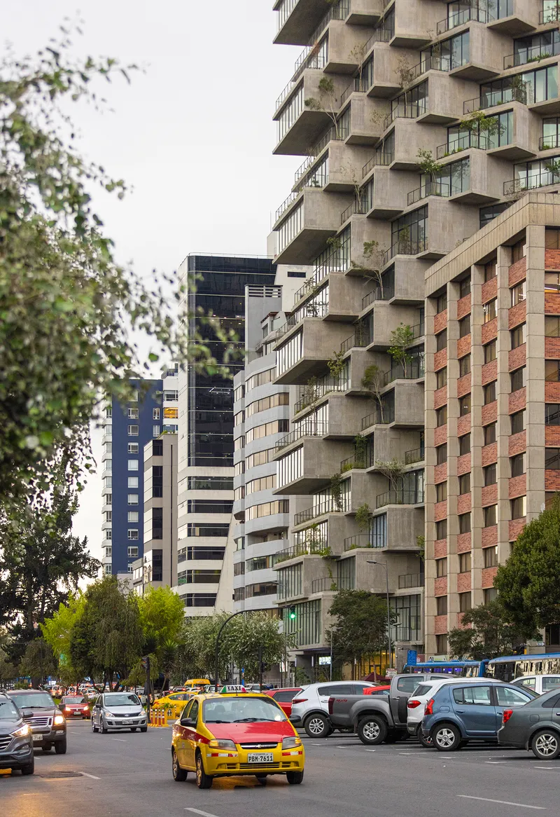 Street view of the stepped balcony facade with trees and yellow taxis in foreground