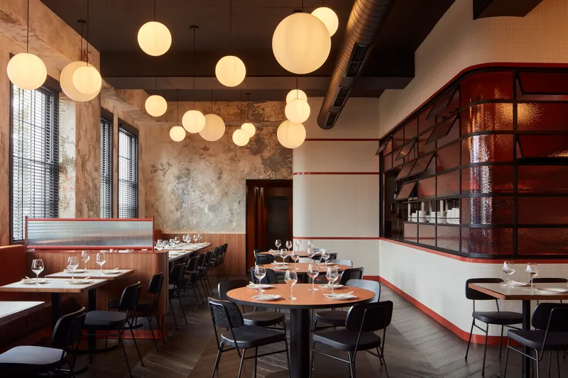 Dining room with sphere pendant lights, distressed plaster walls, and maroon tiled wine display niche