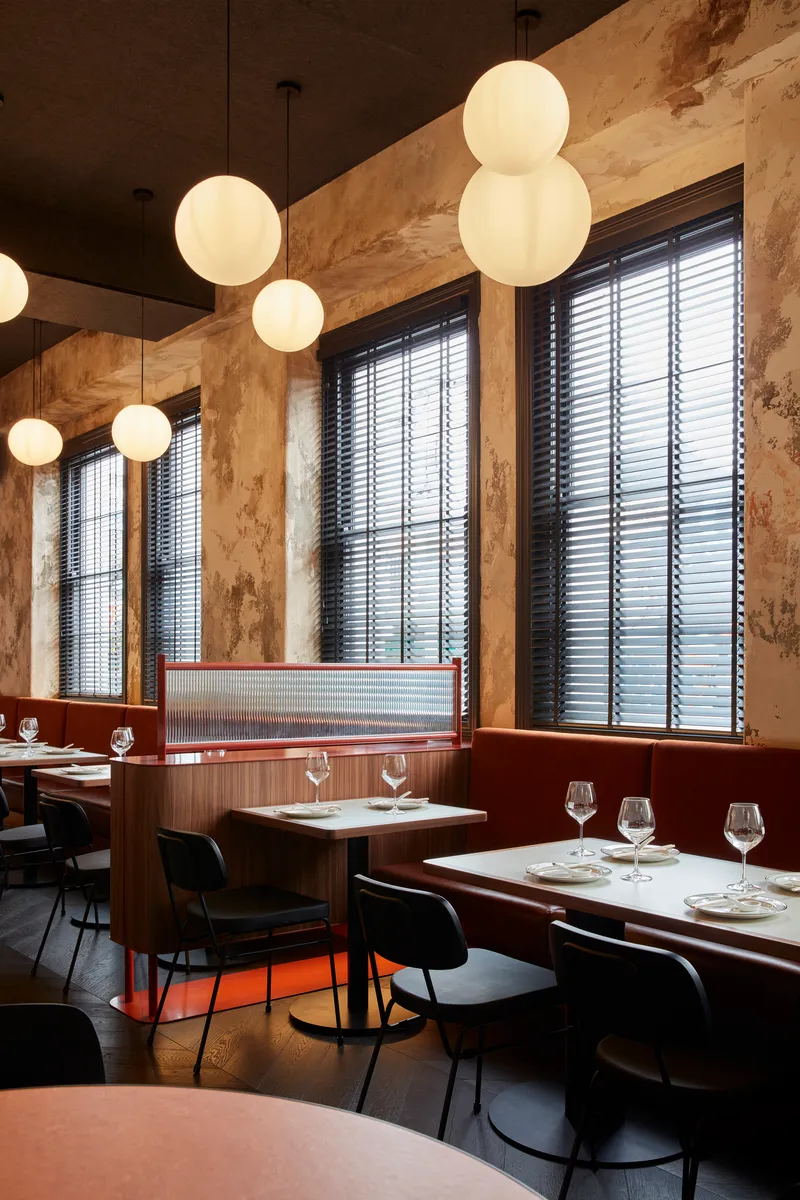 Dining area with globe pendant lights hung beneath dark ceiling and tall windows with horizontal blinds