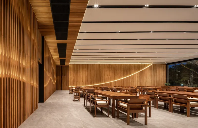 Interior dining hall with vertical wood slat wall and rows of timber benches