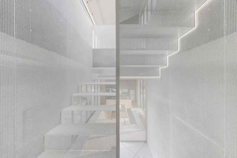 View through translucent perforated metal stair enclosure revealing the dining area beyond