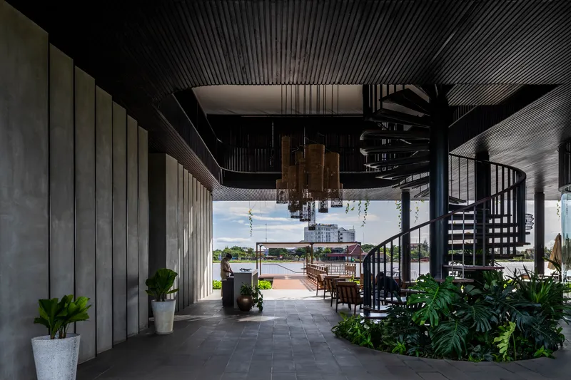 Covered terrace with spiral stair and slatted ceiling overlooking the waterway