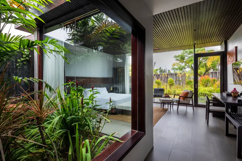 Interior view through planted courtyard to bedroom visible beyond glass partition