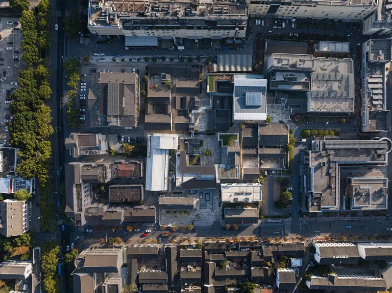 Aerial view of flat rooftops with scattered rooftop gardens in a dense urban block