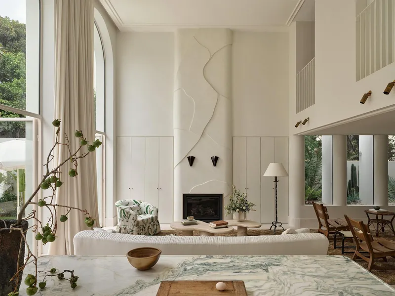 Double-height living room with arched windows, a fireplace, and a sculptural plaster relief above