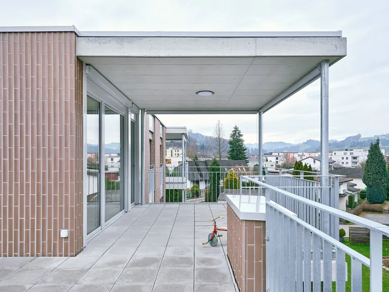 Covered terrace with concrete soffit and white metal railings overlooking the surrounding residential neighborhood