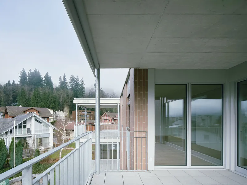 Recessed balcony with concrete soffit and timber cladding column facing a forested hillside