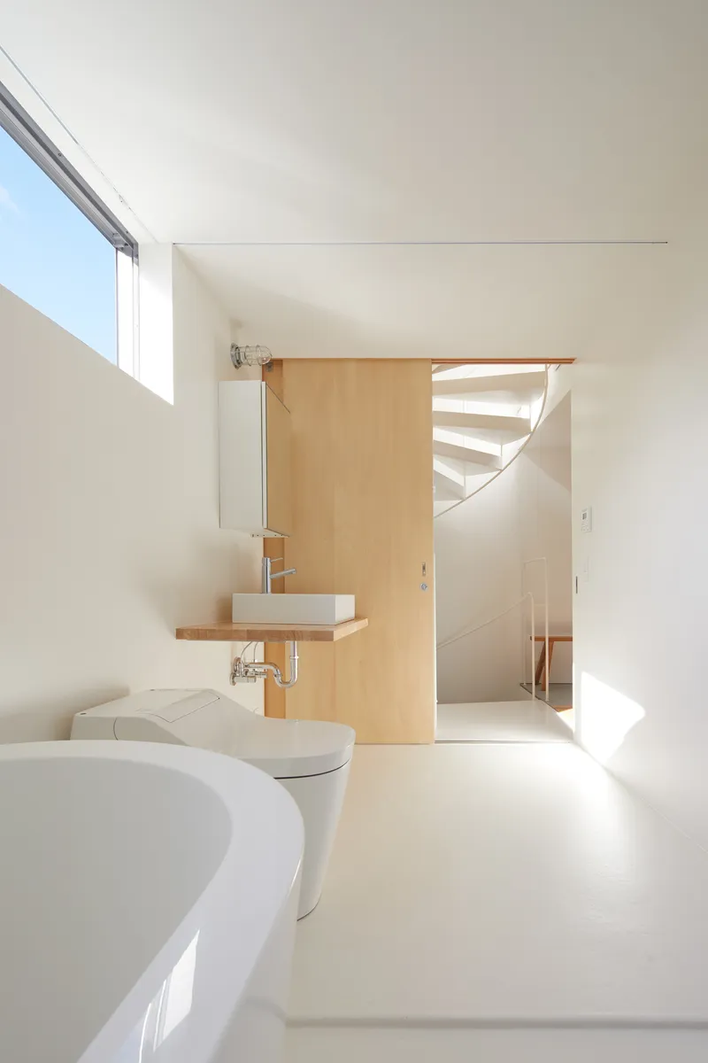 Bathroom with timber partition and floating sink looking toward the spiral staircase beyond