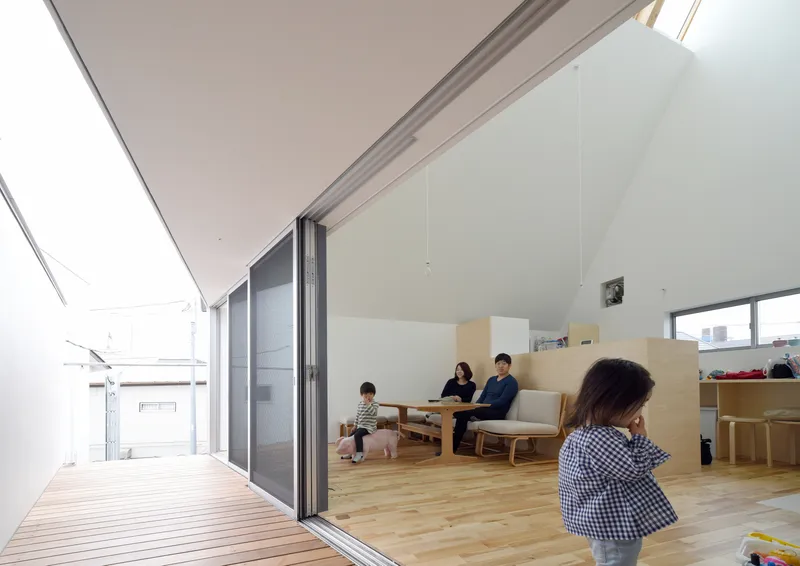 Living area opening to timber deck through sliding glass doors with family seated inside