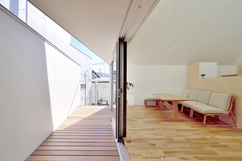 Living room opening through folding glass doors to timber-decked terrace under skylights