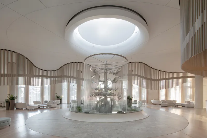 Circular lobby with central fountain beneath a ring skylight and undulating slatted screen