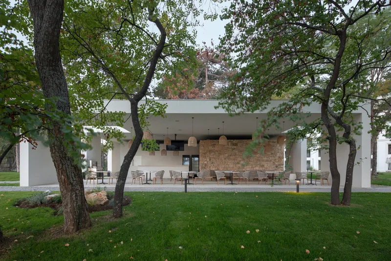 Covered outdoor terrace with stone accent wall and seating area framed by tree canopy