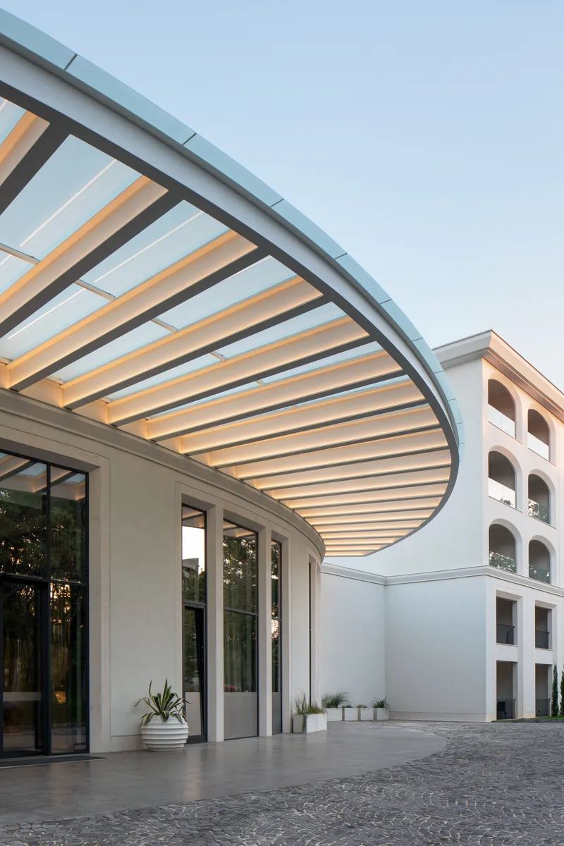 Underside view of the curved canopy showing timber and metal ribs against the evening sky