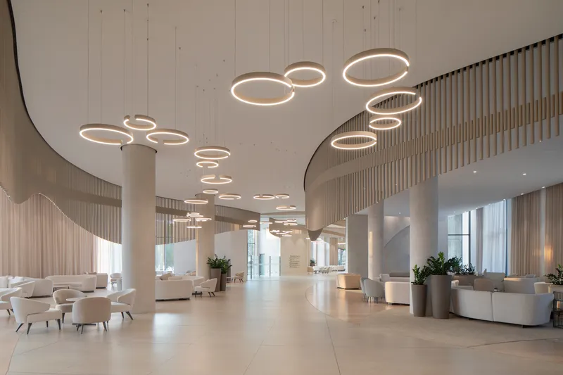 Lobby interior with circular ring pendant lights suspended from a curved soffit above cylindrical columns