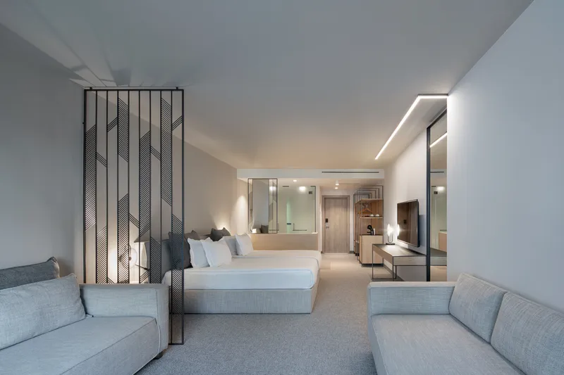 Guest suite with perforated metal room divider separating sleeping area from lounge under recessed ceiling lighting