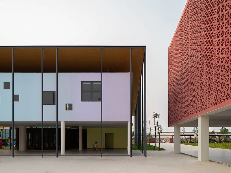 Corner view of the glazed colonnade with pastel panels and perforated terracotta screen volume beyond