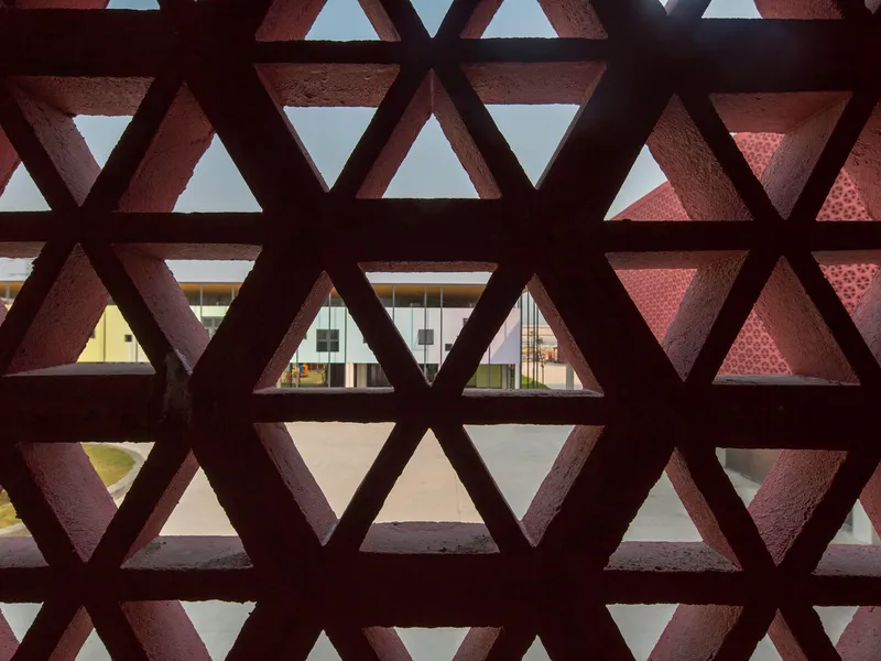 View through triangular lattice screen showing courtyard with another patterned facade beyond