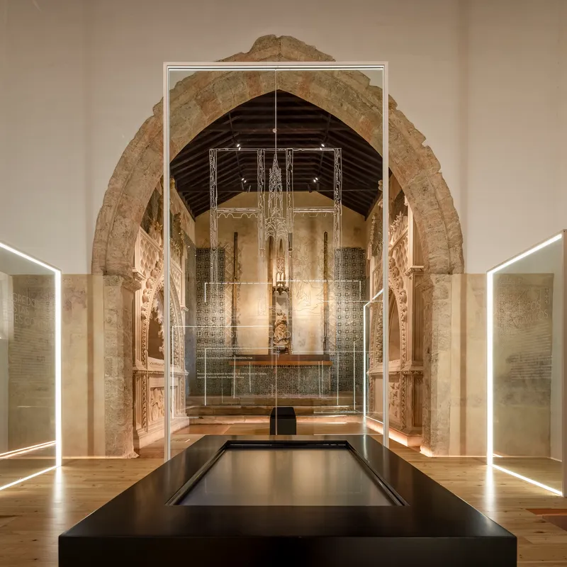 Stone archway framing nave with glass vitrines and timber ceiling at night
