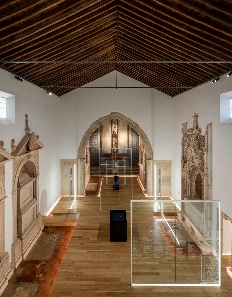 Gallery hall with exposed timber rafters and glass display cases on oak flooring