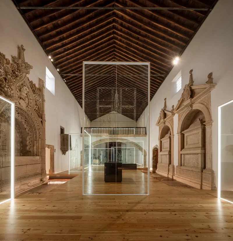 Long view through gallery showing timber ceiling and carved stone portals along walls