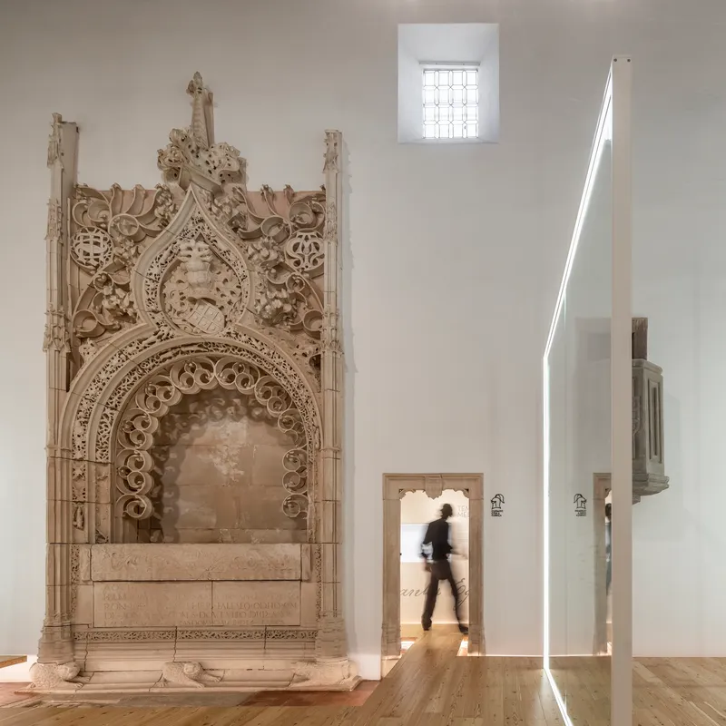 Carved stone portal beside doorway with person walking through backlit opening