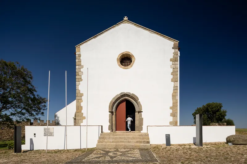 White facade with stone quoins and arched doorway under clear blue sky