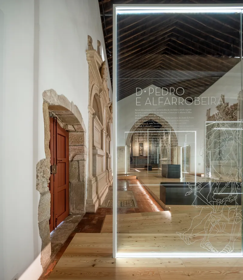 Transparent glass partition with etched graphics framing view of gallery with exposed timber ceiling and stone archway