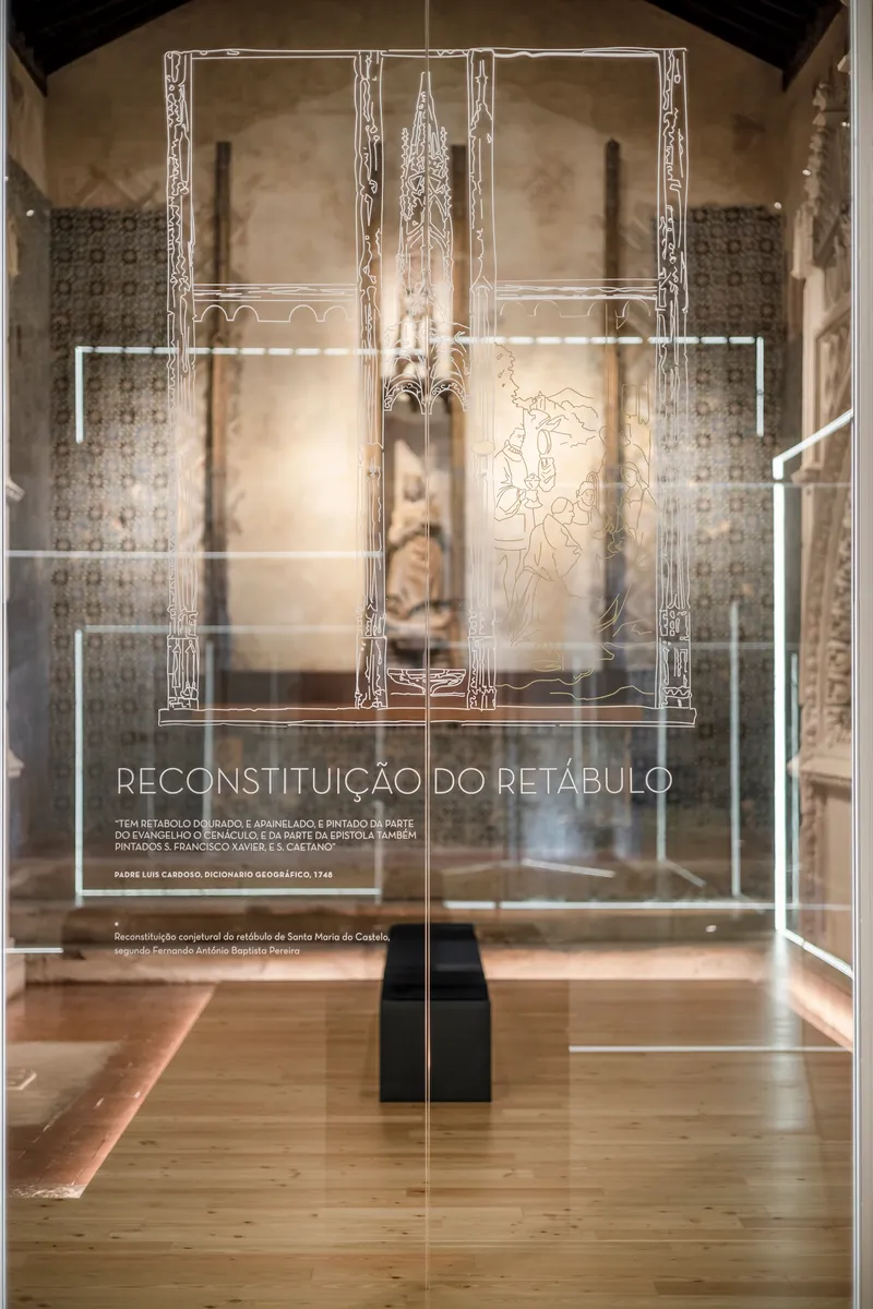 Freestanding illuminated glass display case with decorative line drawings over historic tilework and timber floor