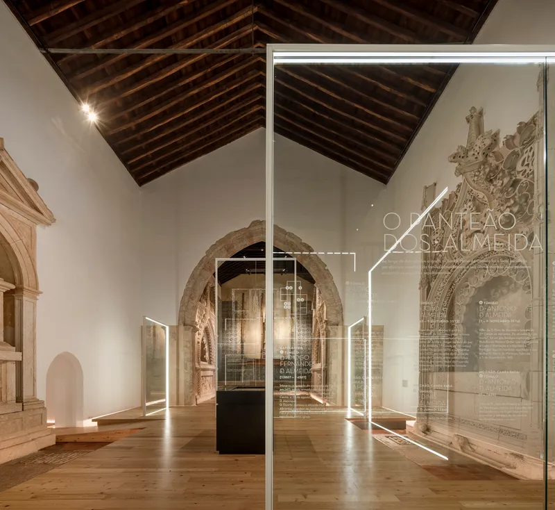 View through glass panels with etched text toward stone arches and dark timber ceiling beams