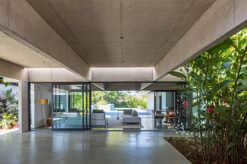 Covered concrete terrace with polished floor opening to an interior courtyard garden of tropical plants