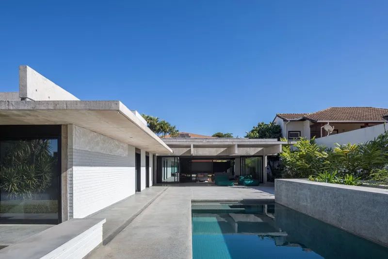 Concrete canopy extending over the pool terrace with glazed openings framing the interior spaces