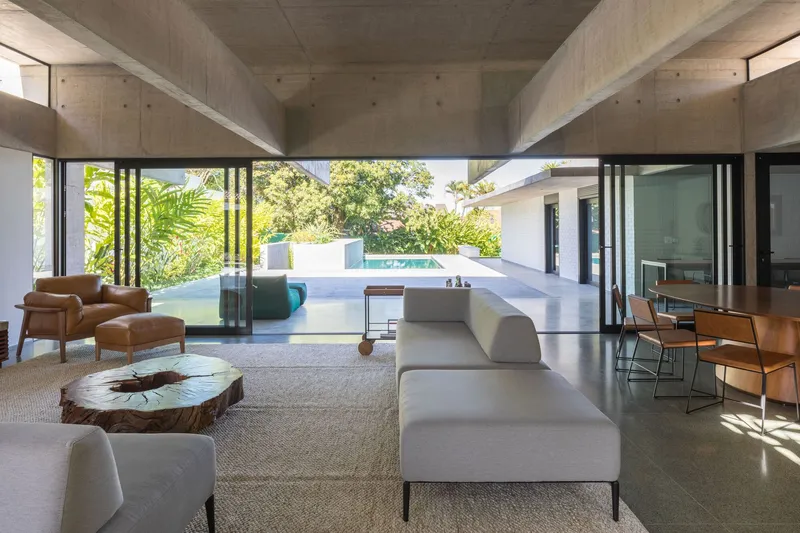 Open-plan living space with folding glass doors framing a view of the swimming pool and landscape