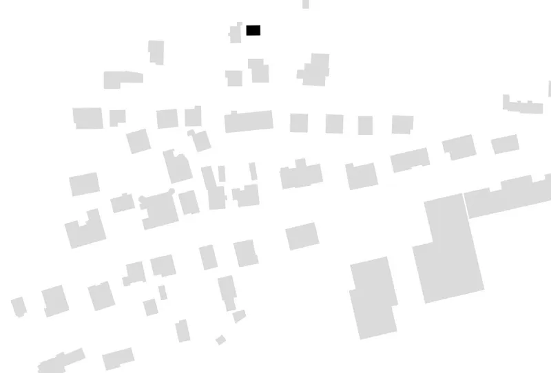 Site plan showing rectangular building footprints scattered along a sloping street with one highlighted in black