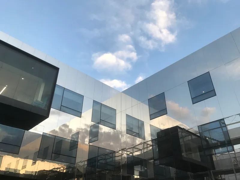 Courtyard facade with scattered box windows reflecting clouds at late afternoon