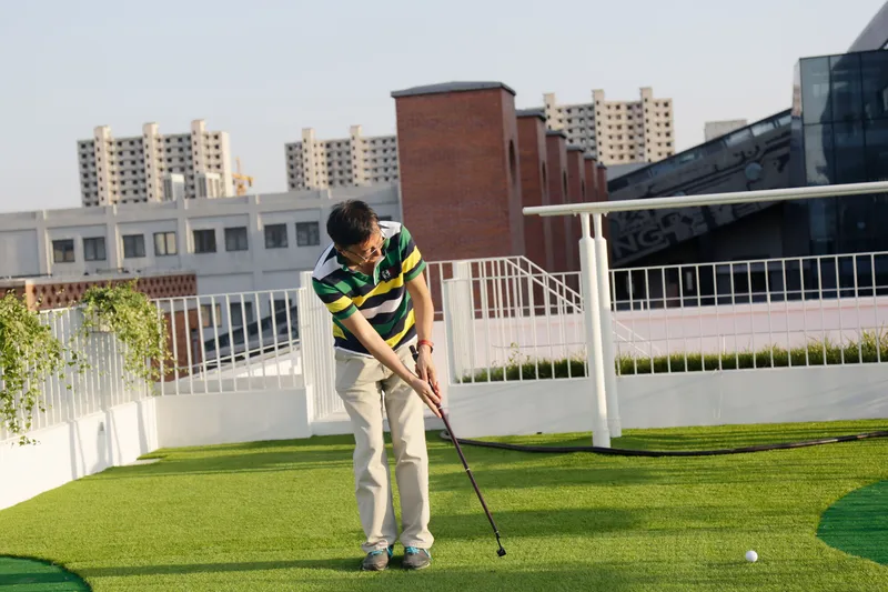 Rooftop putting green with white railings and residential towers in the background