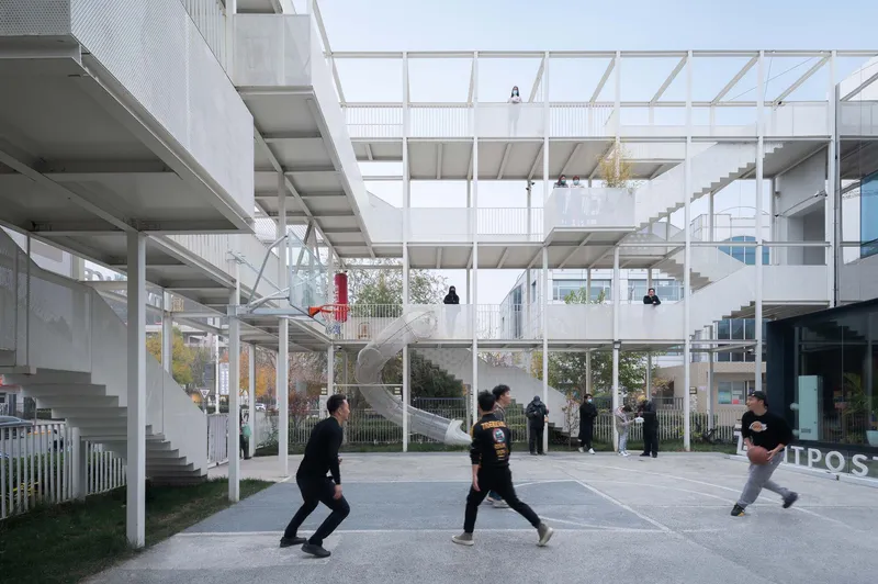 Courtyard with people playing basketball beneath the open steel framework and suspended pendant lights