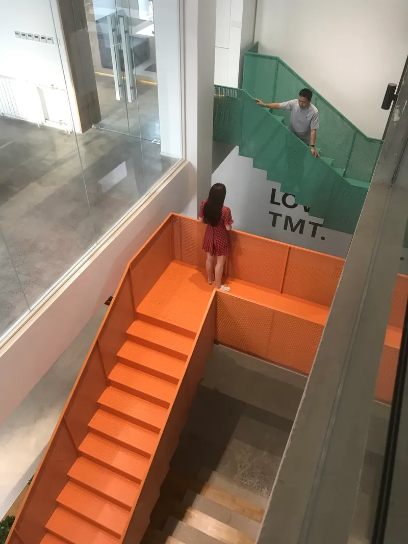 Interior view of orange and green powder-coated steel staircases with two people ascending
