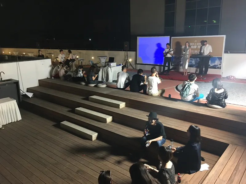 Timber bench seating facing an outdoor projection screen during an evening presentation