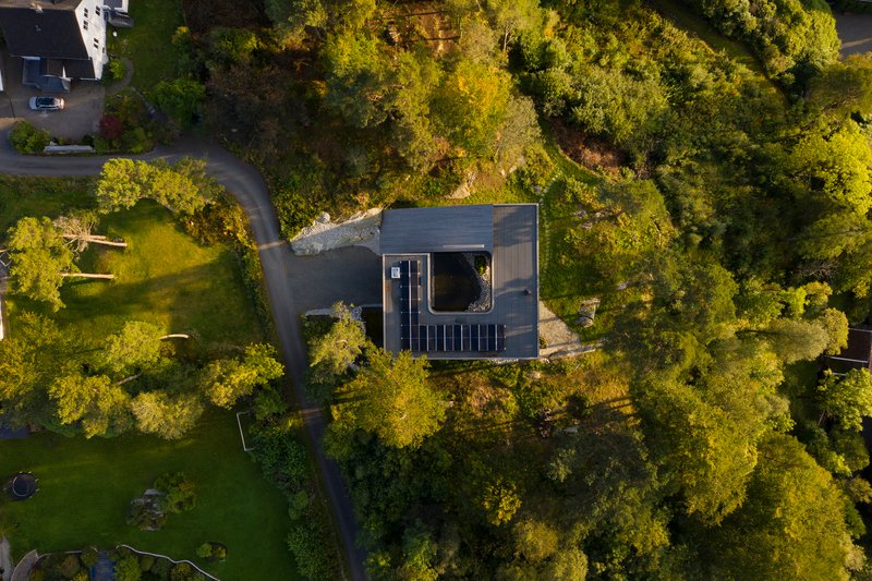 Aerial view of the dark timber roof with central courtyard opening nestled among dense forest
