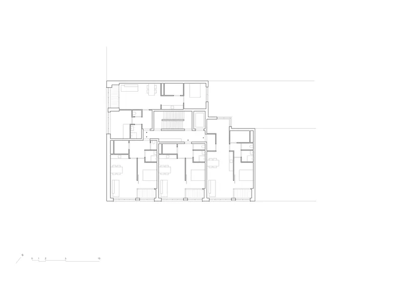 Floor plan drawing depicting residential units with central staircase and multiple bedroom layouts