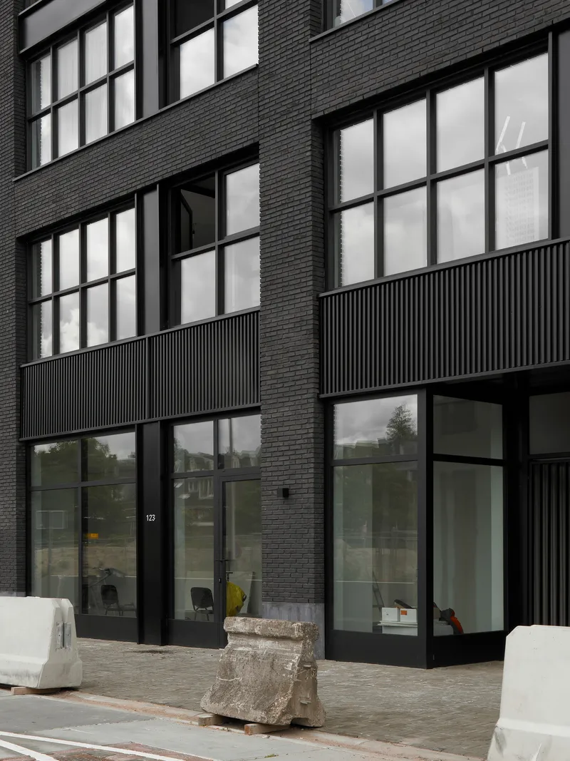 Ground floor entrance with black-framed glazing, fluted metal panels, and dark brick facade