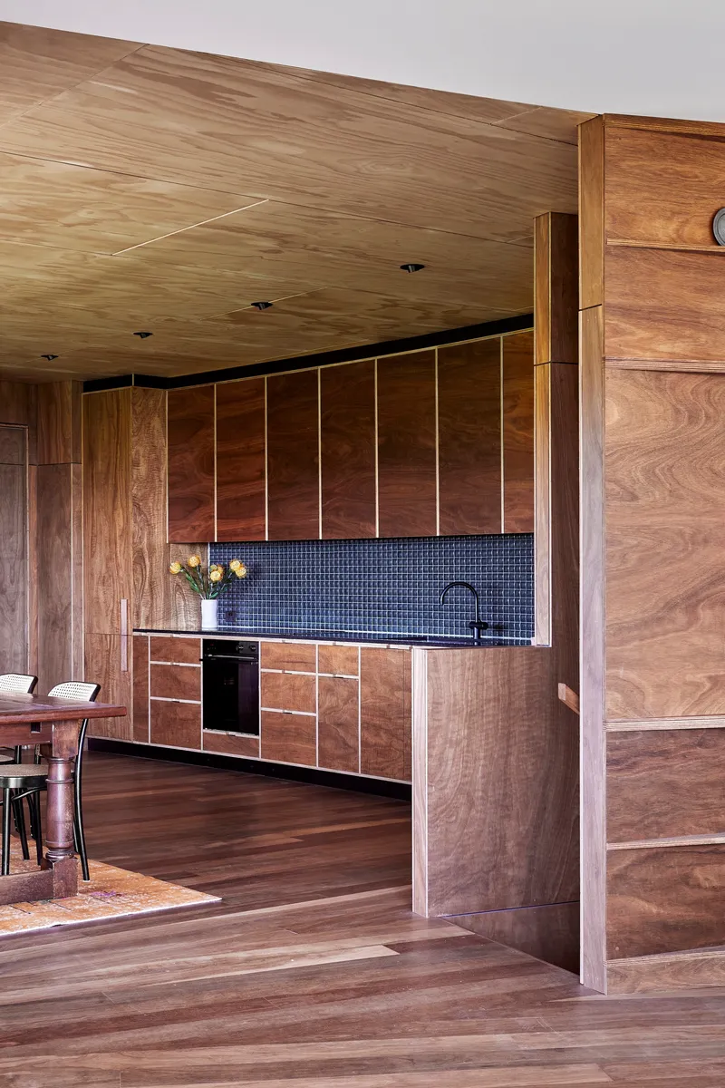 Timber-lined kitchen with dark mosaic tile backsplash and continuous plywood ceiling