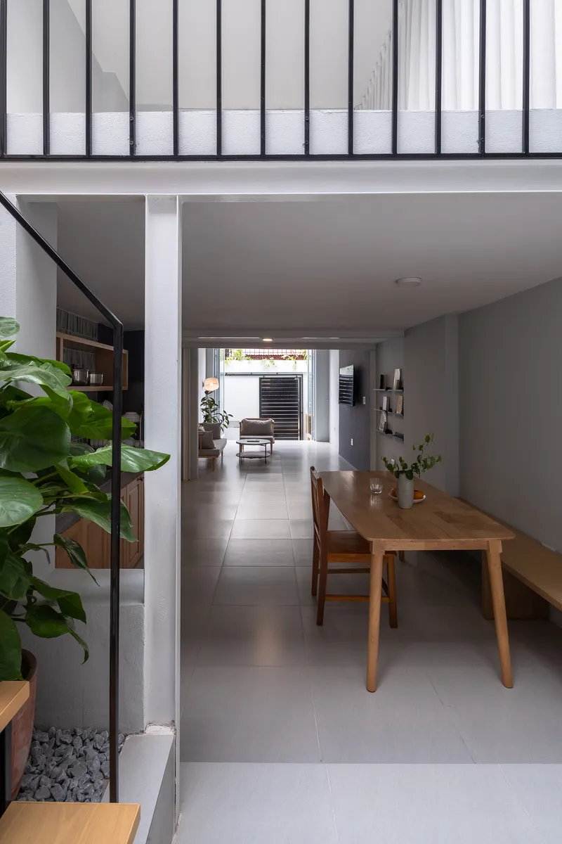 Open dining area with timber table and grey tile floor beneath a steel-framed clerestory window