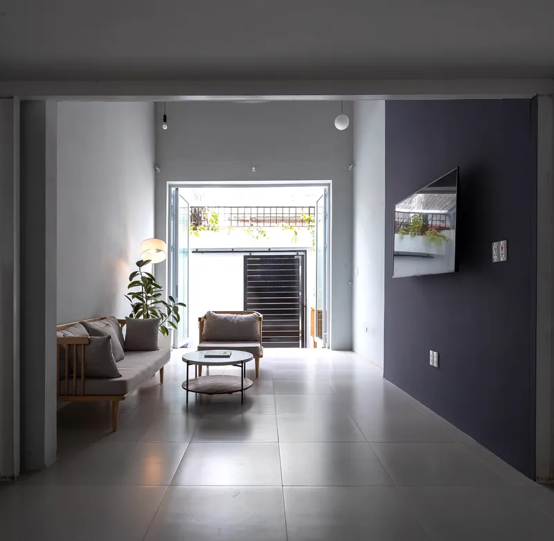 Living room with grey tile floor looking toward open doorway with louvered screening beyond