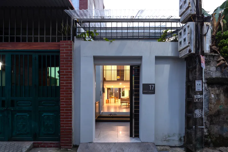 Street facade with central entrance opening showing illuminated interior passage at dusk